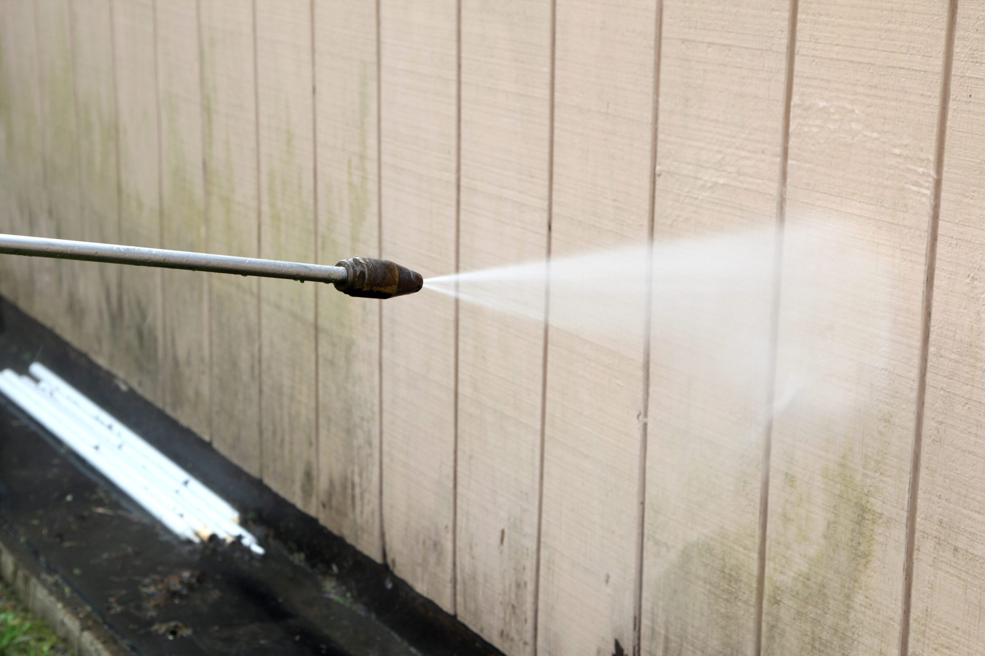 Pressure washer being used on siding.