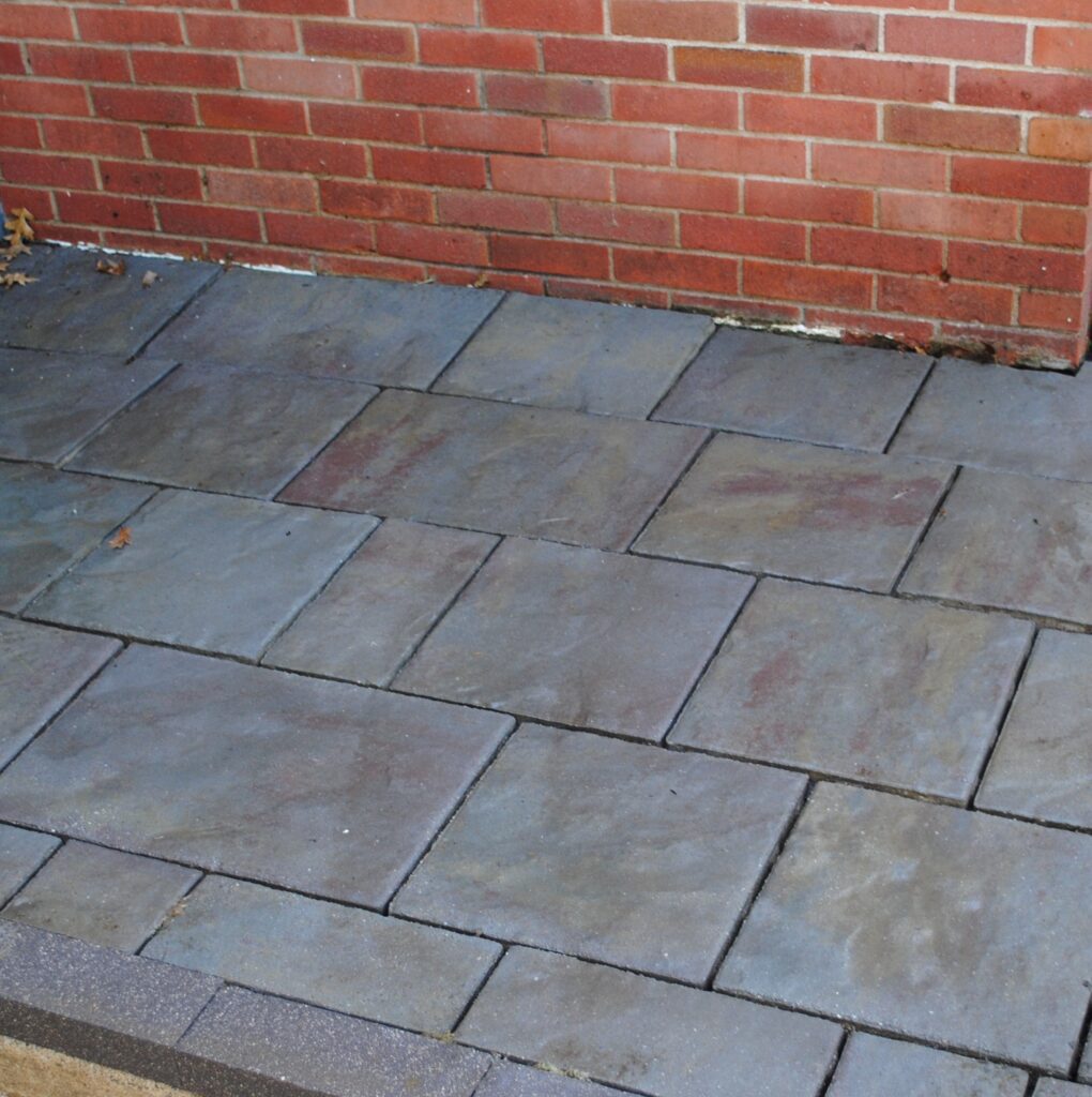 Stone patio pavers beside red brick wall