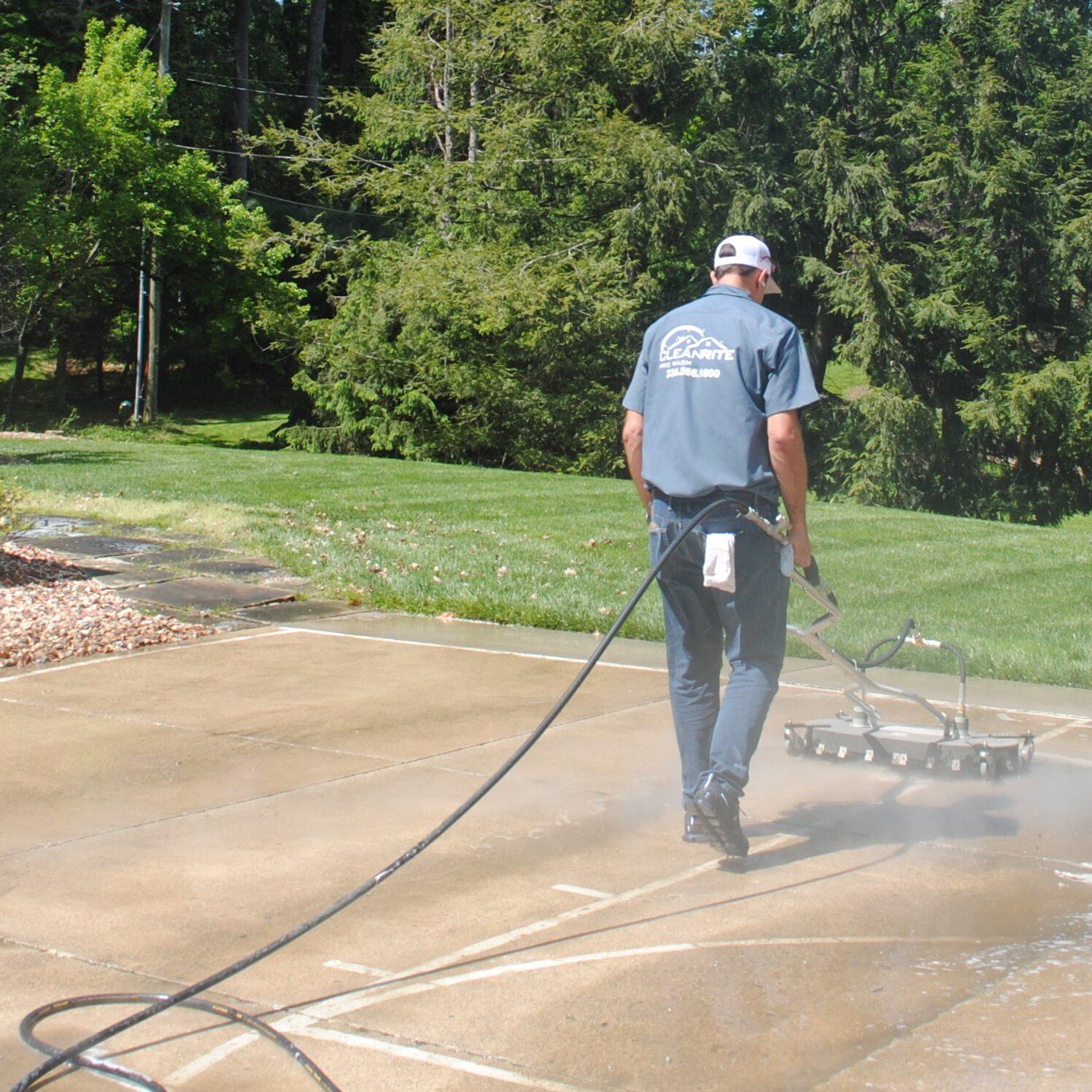 Worker pressure washing driveway with surface cleaner